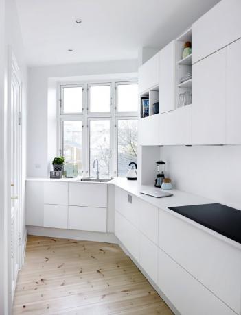 Et hvitt kjøkkensett i interiøret kan fortynnes med treelementer, svarte husholdningsapparater